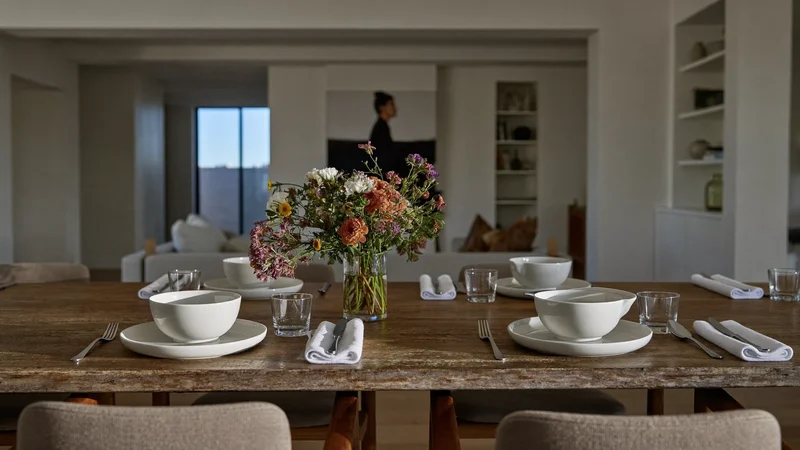 Gedeckter Tisch für zwei mit Suppenterrine, Stoffservietten und Blumenvase